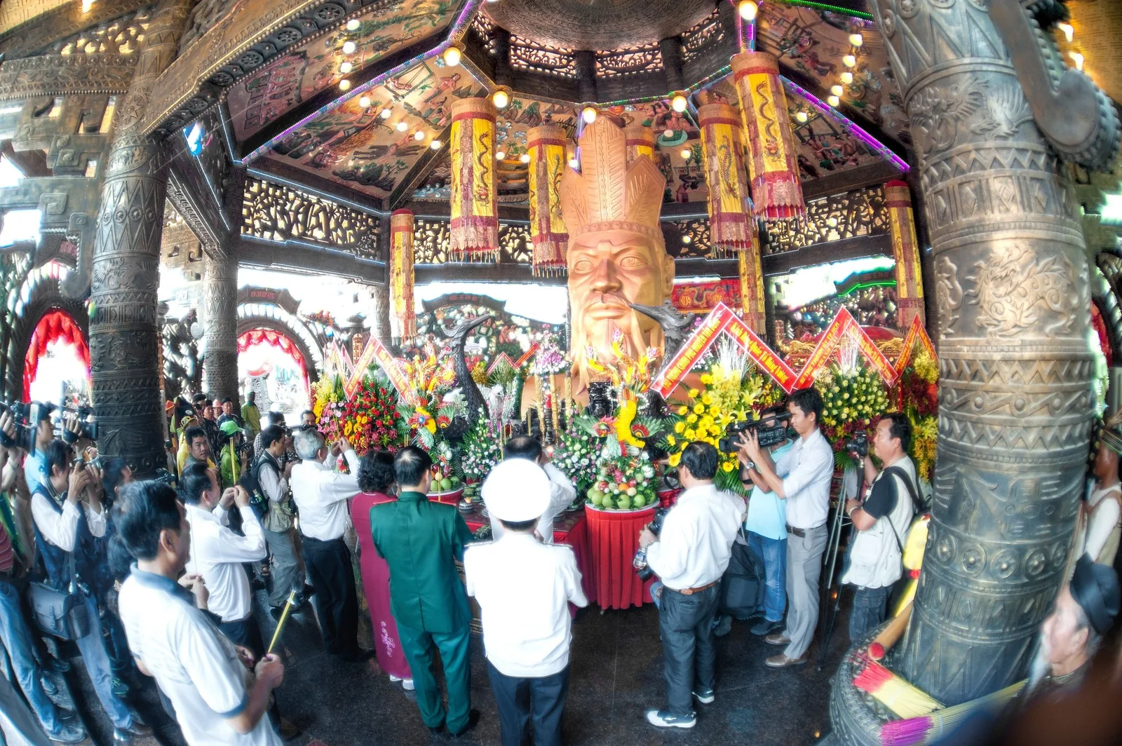 Đông người tập trung quanh tượng vua bằng gỗ chạm khắc lớn và hoa cúng trong đền thờ Hùng Vương ở Phú Thọ.