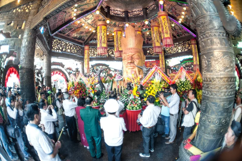 Đông người tập trung quanh tượng vua bằng gỗ chạm khắc lớn và hoa cúng trong đền thờ Hùng Vương ở Phú Thọ.