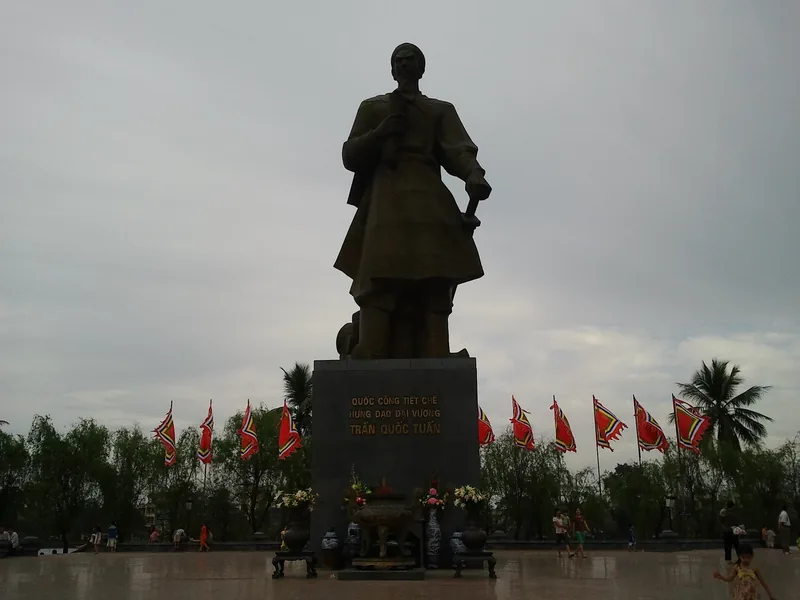 Tượng đài Trần Quốc Tuấn sừng sững trên quảng trường ở Nam Định, hai bên có cờ lễ.