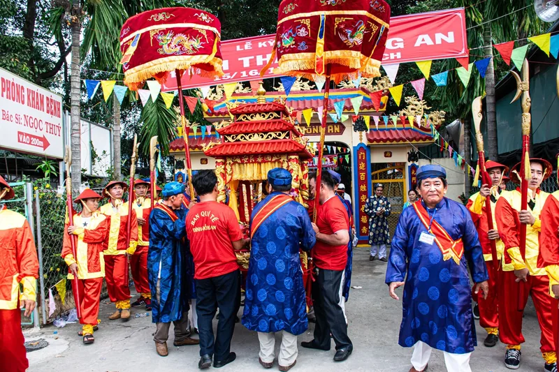Những người đàn ông mặc trang phục truyền thống đỏ và xanh khiêng kiệu rước trong lễ hội làng ở Việt Nam.