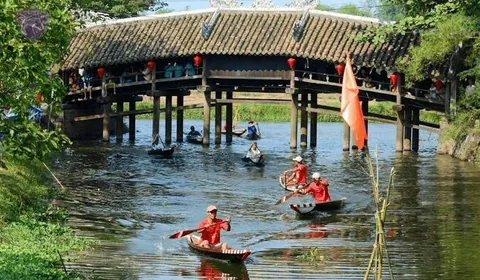 Những người đua thuyền chèo dưới mái ngói cầu Thanh Toàn trên dòng sông gần Huế.