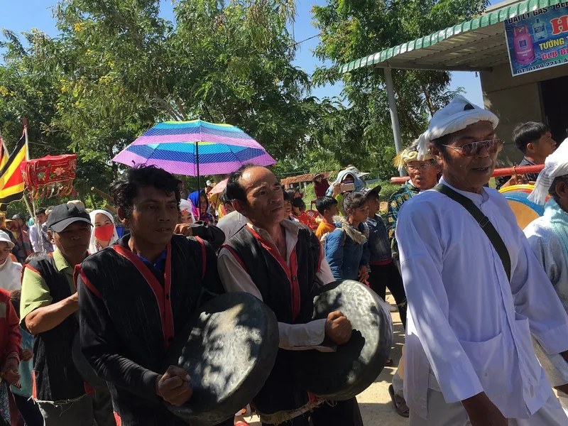 Những người đàn ông mặc trang phục truyền thống mang cồng diễu hành trong lễ hội Kate ở Ninh Thuận.