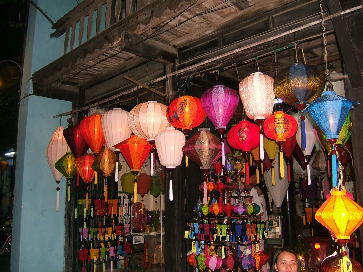 Những chiếc đèn lồng lụa nhiều màu sắc treo trước một cửa hàng gỗ vào ban đêm ở Hội An.