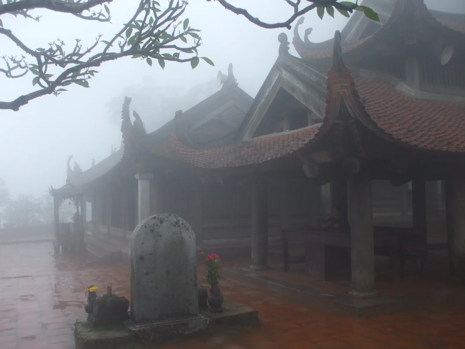 Sương mù bao phủ mái ngói cong và bia đá của chùa Hoa Yên trên núi Yên Tử.