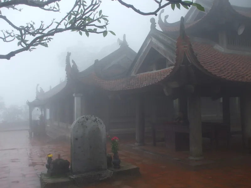 Sương mù bao phủ mái ngói cong và bia đá của chùa Hoa Yên trên núi Yên Tử.